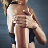 Female athlete manages shoulder pain with massage