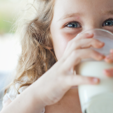 Small girl drinking a glass of vitamin D fortified milk