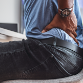 Man working from home back pain caused by poor ergonomics.